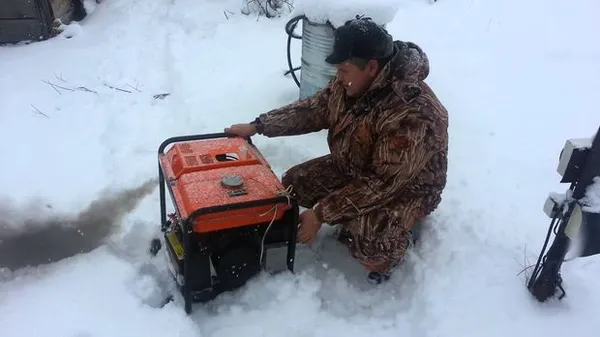 Мужчина заводит бензиновый генератор в мороз