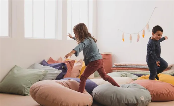 Дети прыгают на подушках в детской комнате